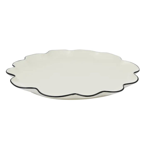 White scalloped-edge plate with black rim on a white background